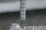 High-precision CNC end mill positioned above a machined aluminium component inside a modern industrial environment