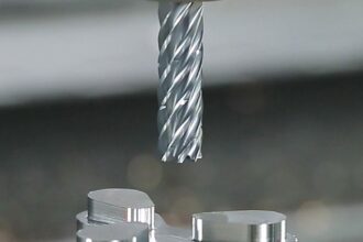 High-precision CNC end mill positioned above a machined aluminium component inside a modern industrial environment
