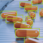 MVTec HALCON 26.05 AI object detection software identifying capsules on a high-speed pharmaceutical production line using machine vision technology