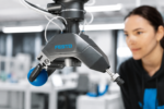Festo GripperAI robotic gripper using AI vision to identify and handle mixed objects while an engineer monitors the system.